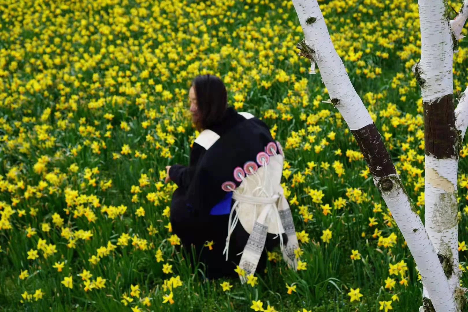 A woman wearing Naxi-inspired dress standing in a field of flowers